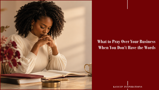 A woman with her hands folded in prayer over an open journal, a cup and red flowers on the desk.